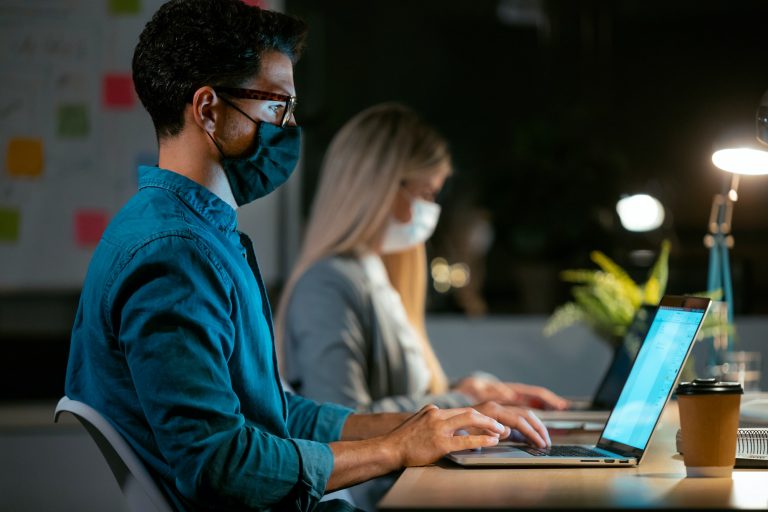 concentrated business team wearing a hygienic facial mask while working with laptops